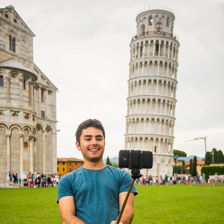 man taking selfie in front of the leaning tower of pisa