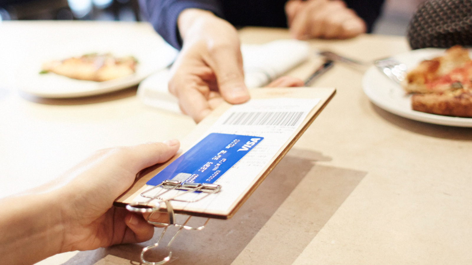 Person paying with Visa card over the counter.