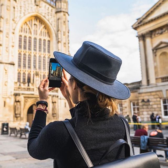 tourist taking picture on phone in city of bath